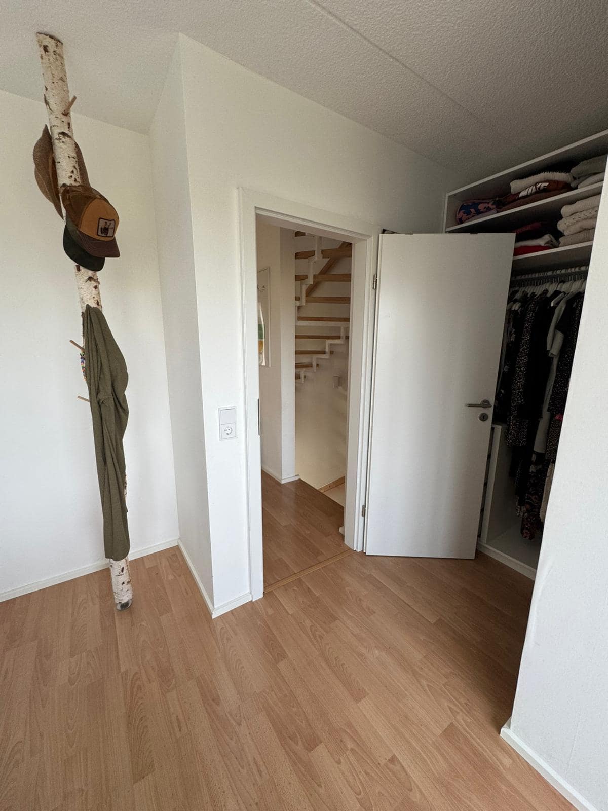 Fertig eingebaute Zimmertür mit weißem Rahmen, Blick in den Flur mit Laminatboden.