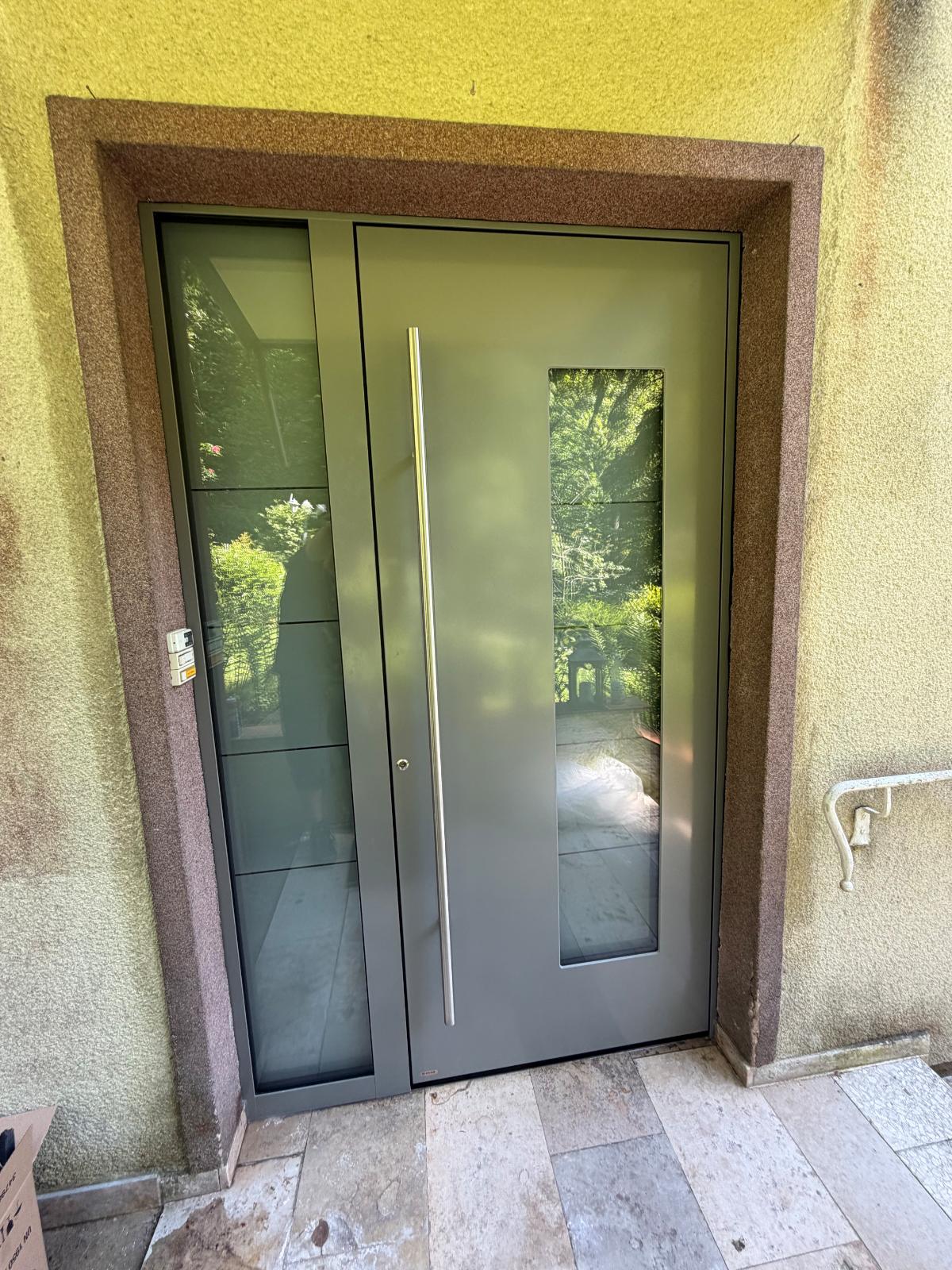 Neue Aluminium-Haustür in Anthrazit mit Glasausschnitt, Seitenteil und Edelstahl-Stoßgriff, fertig montiert in Natursteinlaibung.